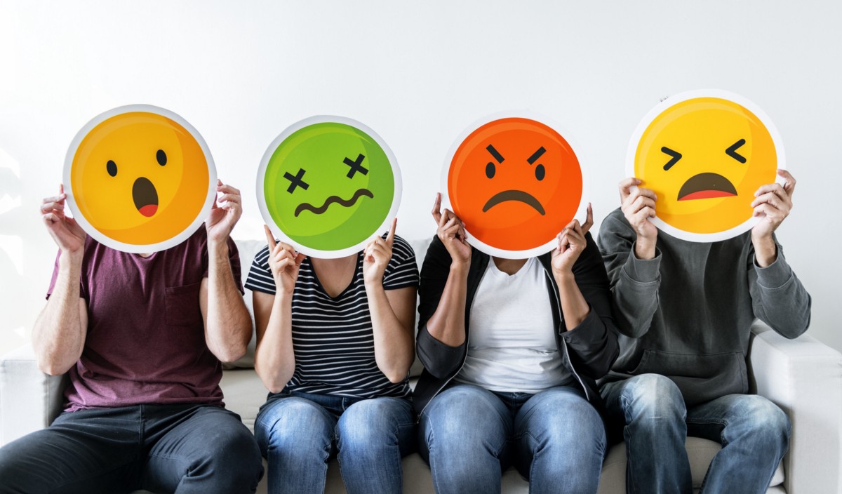 People holding up emoji masks showing surprised, annoyed, frustrated and angry faces